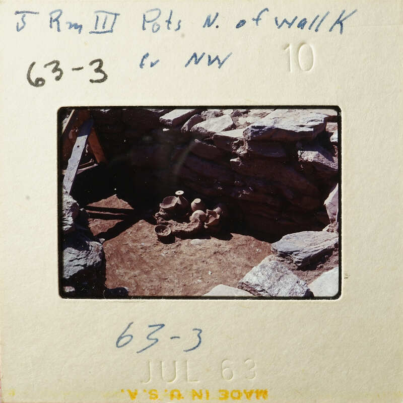 This is an old photograph showing a stone structure with a dirt floor, possibly a historical site.