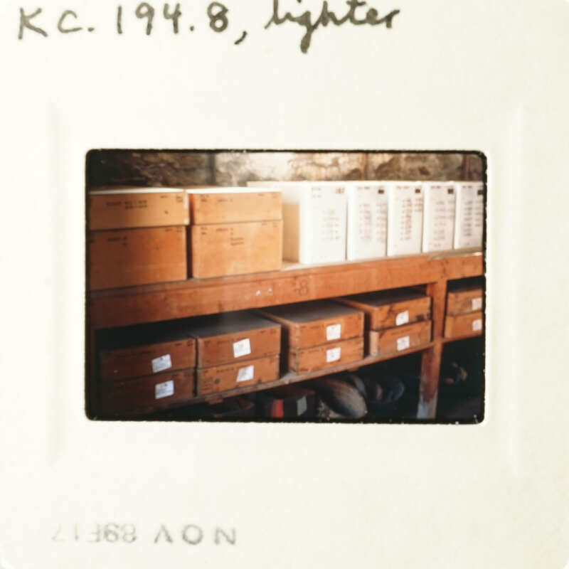 A photograph of a wooden shelf filled with boxes, taken from an angle above the items.