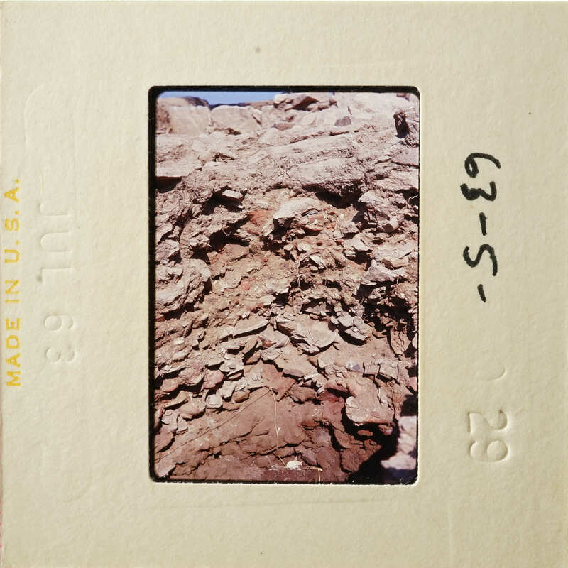 A photograph of an old rock formation with layers and textures, captured on film.