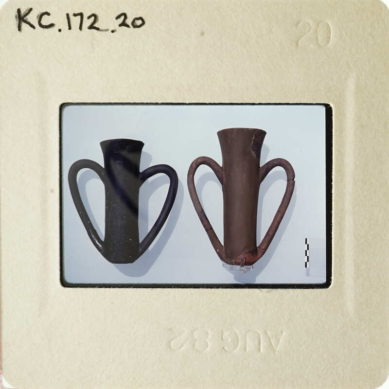 Two ceramic vases on a white surface, with one being larger and having handles.