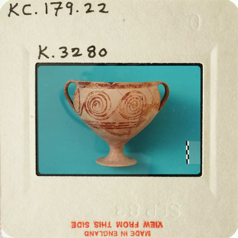 Ancient Greek vase with intricate designs and facial motifs.