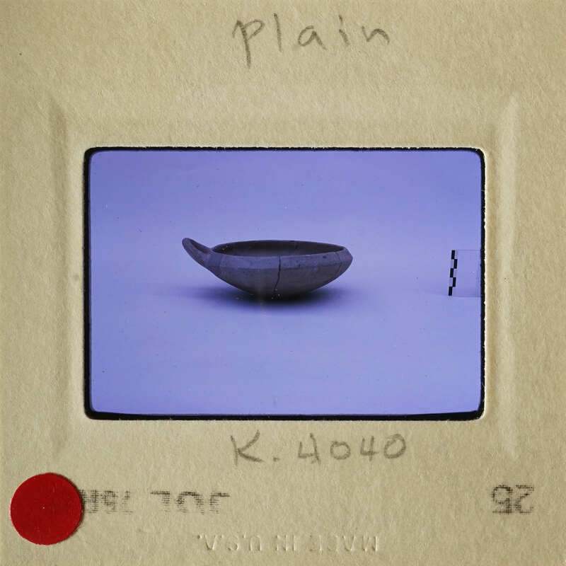 A photograph of an ancient bowl with a visible crack and chip, displayed on a plain background.