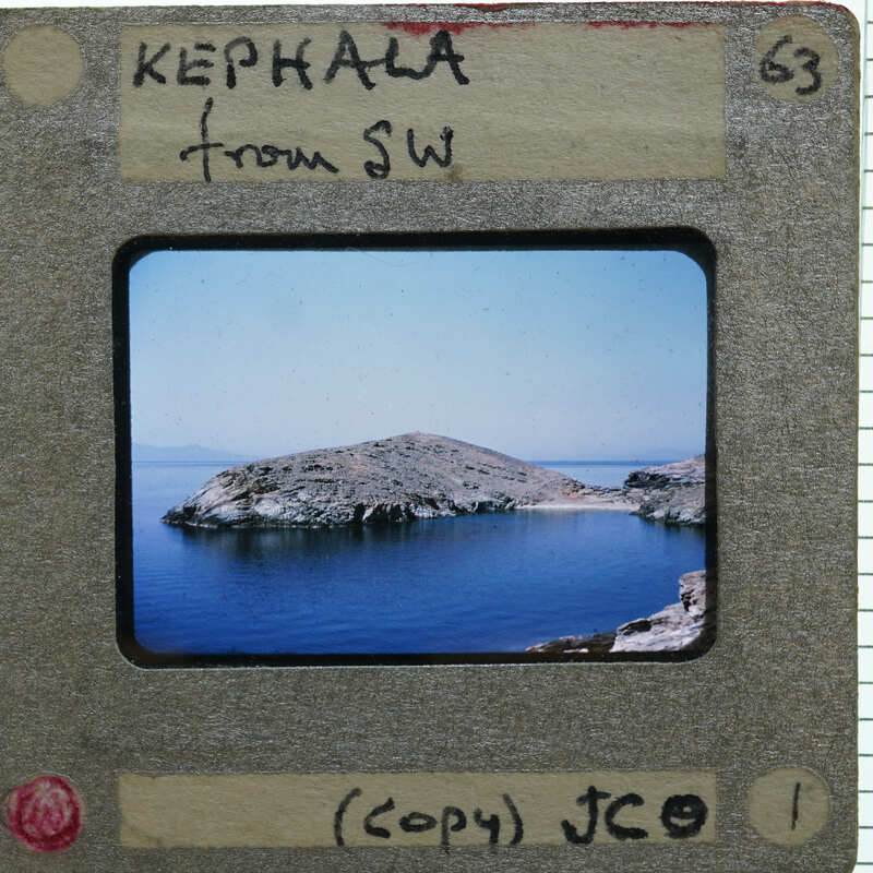 A vintage photograph of a rocky island in the ocean, with handwritten notes on its borders.