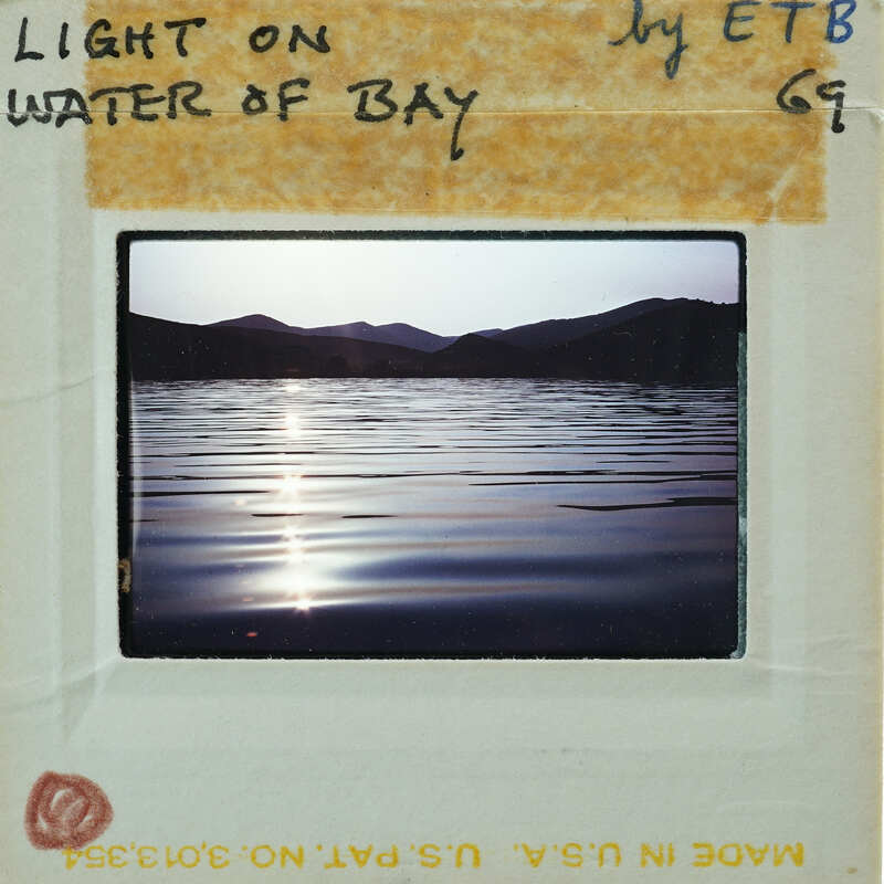 Photo of a serene lake at sunset with mountains in the background, presented as a Polaroid-style image on a white card.