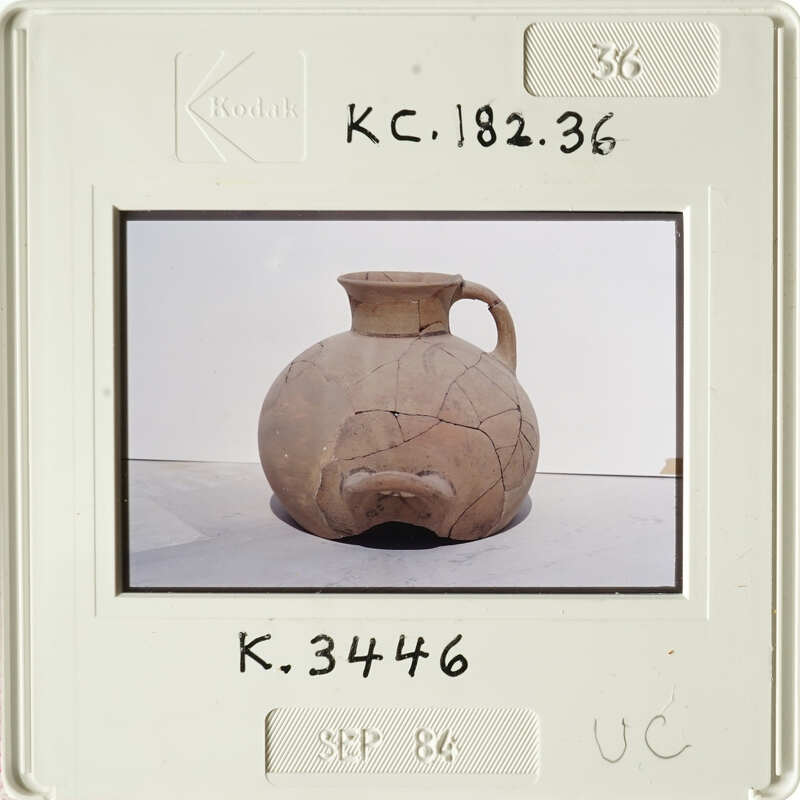 Ancient clay pot with visible cracks and imperfections, photographed on a white surface.