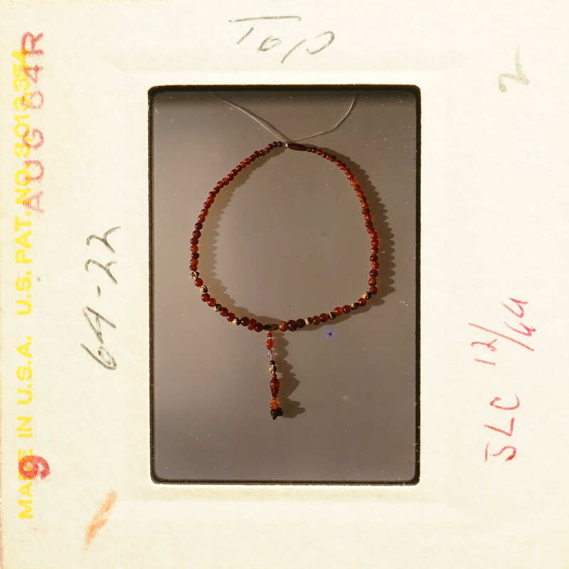 A bracelet with red beads and a clasp, displayed on a white background.
