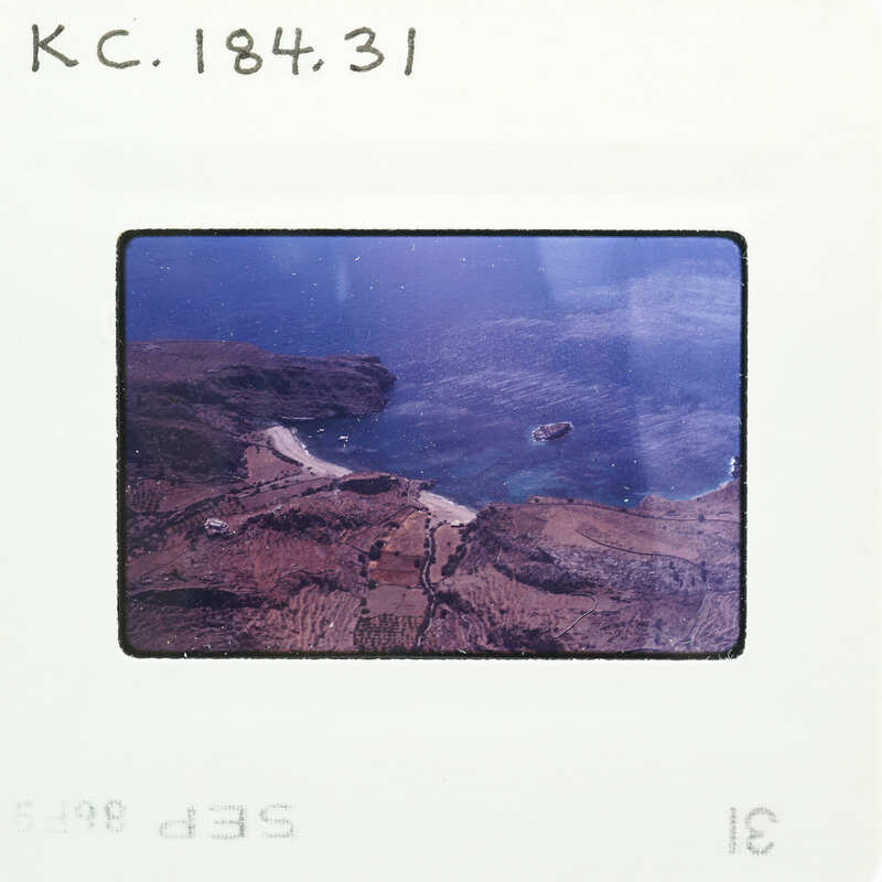 Aerial view of a coastline with land, sea, and boats.