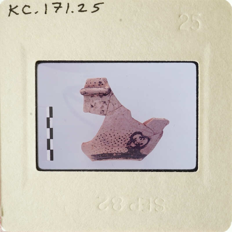 Ancient pottery artifact with markings, photographed on a white background.