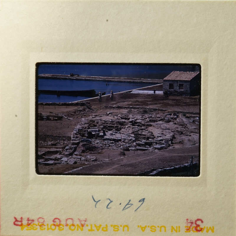 Aerial view of ancient ruins and water body, possibly from an archaeological site.