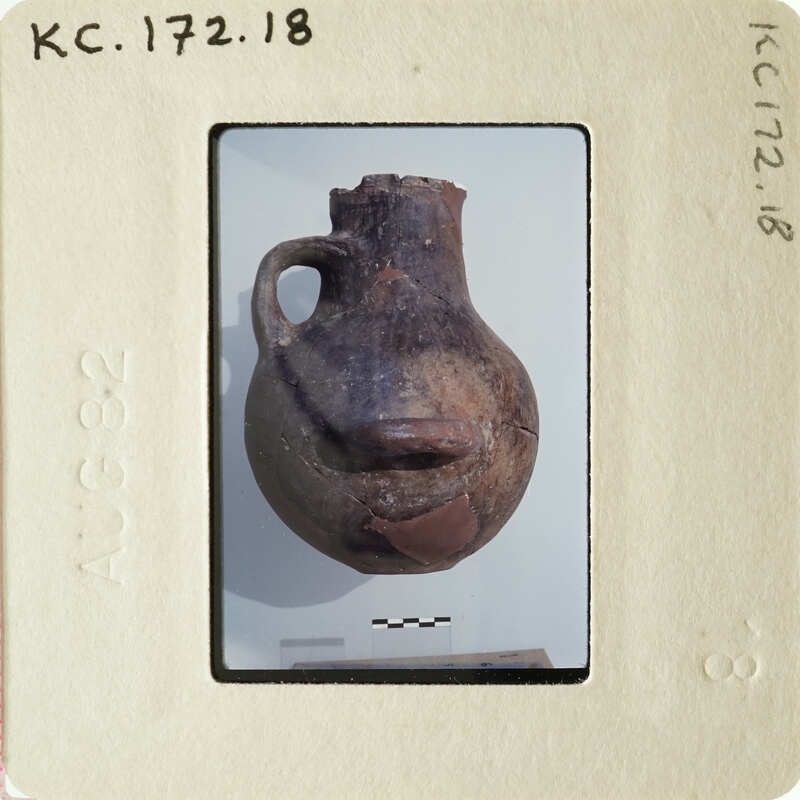 Old clay pot with handle and mouth, displayed on white background.