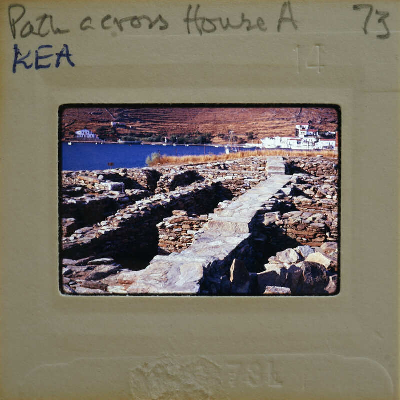 A photograph of a stone path leading to ruins by the water.