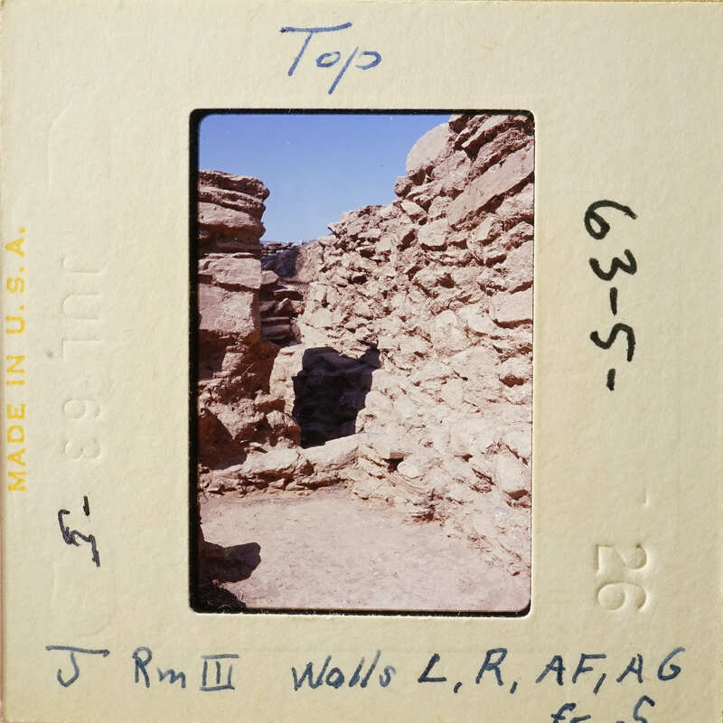 Old stone ruins with blue sky and desert ground.