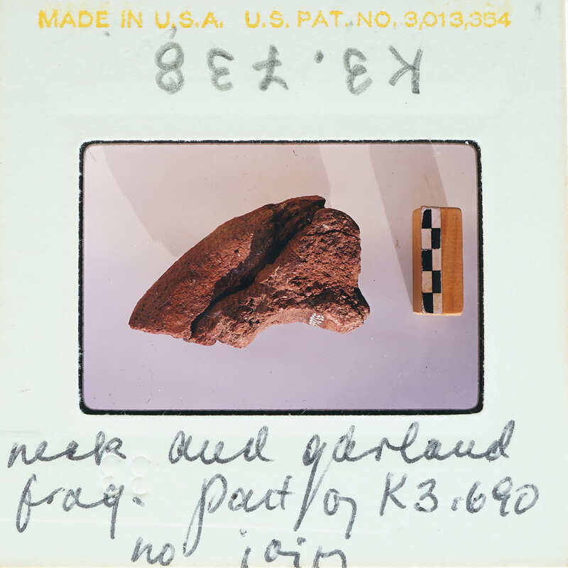 A photograph of a large, ancient stone artifact with handwritten notes and labels.