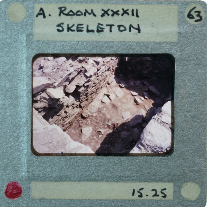 A photo of a room with stone walls and floor, displayed on an old film strip labeled "A ROOM XXXII".