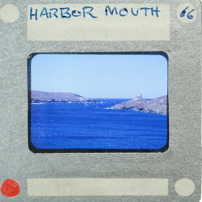 A vintage film strip showing a scenic harbor with blue water and land formations in the background.