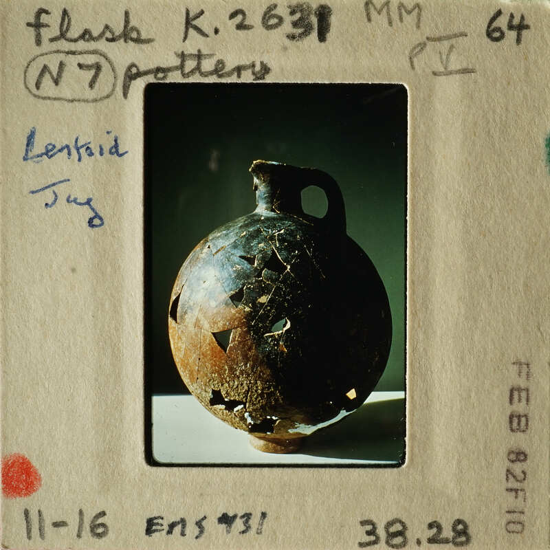 Ancient pottery artifact with visible cracks and chips, displayed on a white surface.