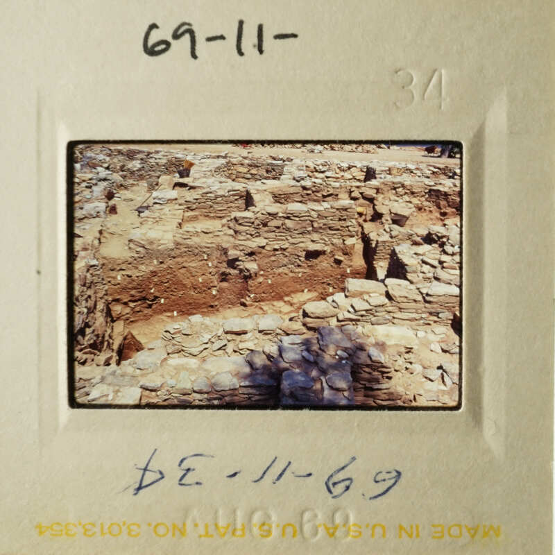 The photograph shows an ancient stone structure, possibly ruins, with layers of brick and stone, taken from a distance.