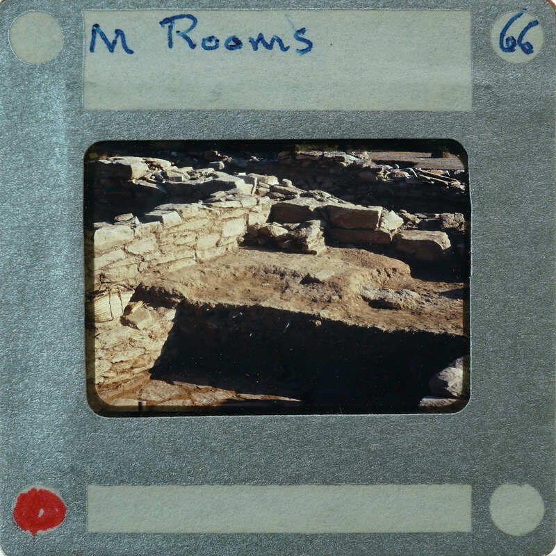 A photograph of an archaeological site with ruins and excavated areas, presented on a vintage film strip card.