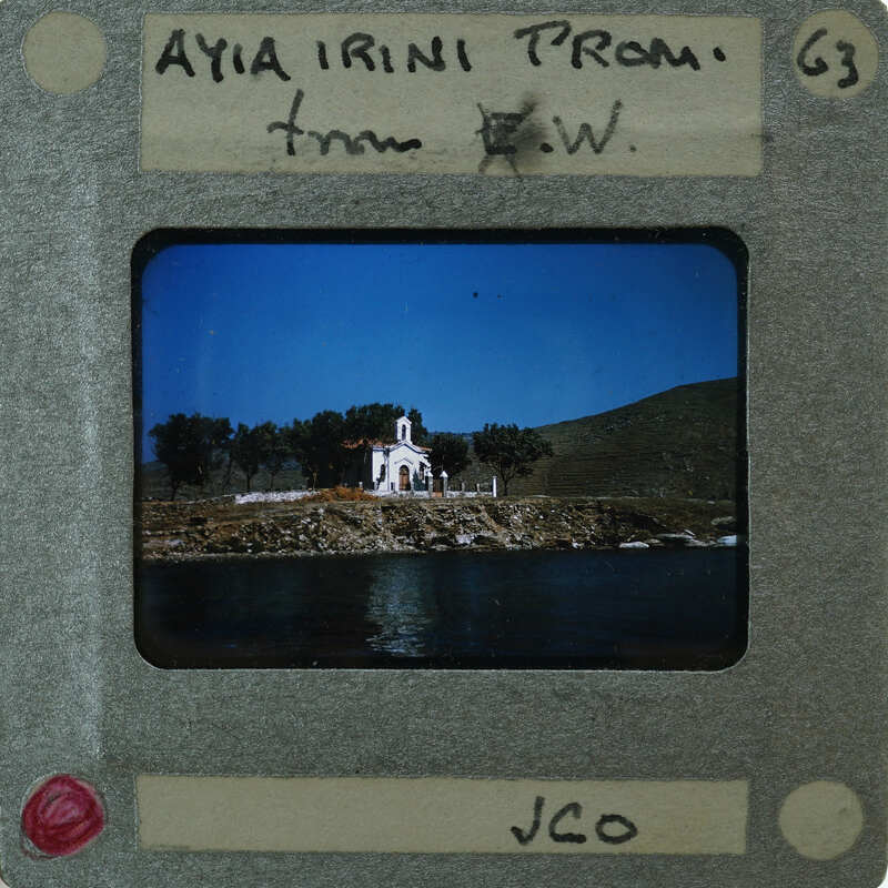 A vintage photo of a coastal town with a church on a hillside, enclosed by a film strip frame.