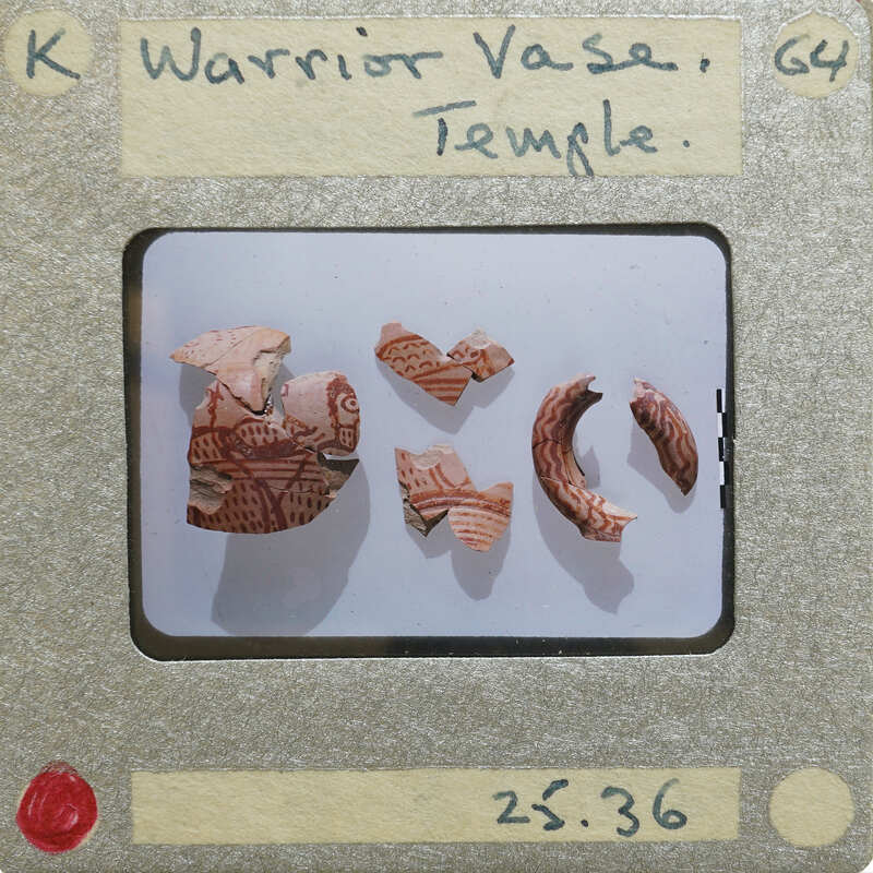 Unassembled fragments of vase with lines and warrior motif in red paint.