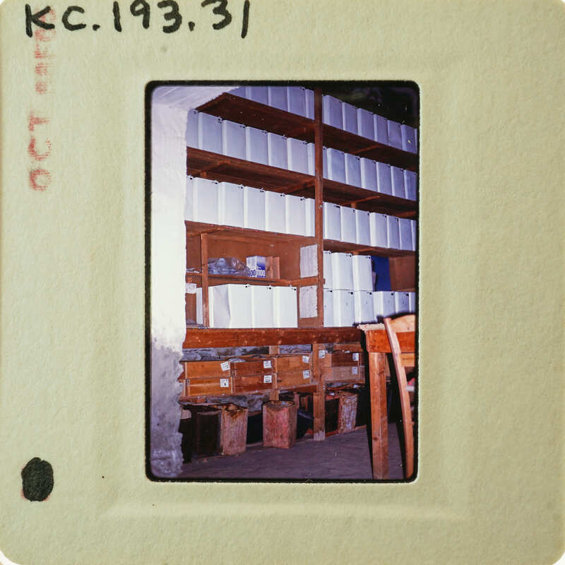 A photograph of a storage room with shelves filled with boxes and papers, taken on film.