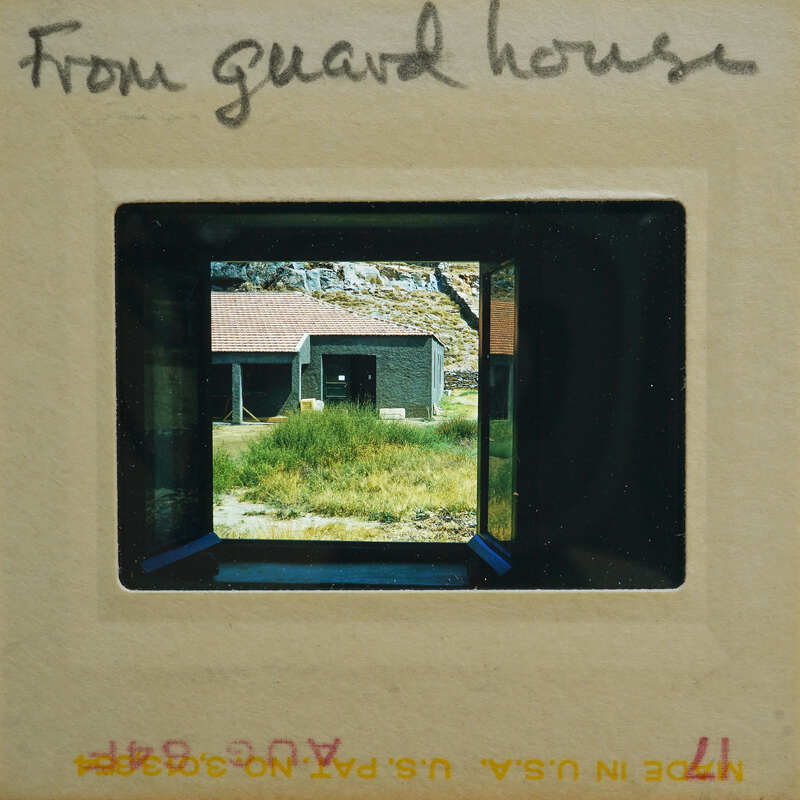 Picture of a guard house with a view of a building and grass through the window.