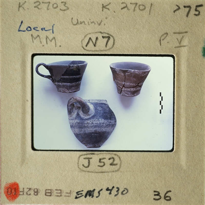Old broken pottery displayed on a white surface with labels and numbers indicating their identification for study or collection purposes.