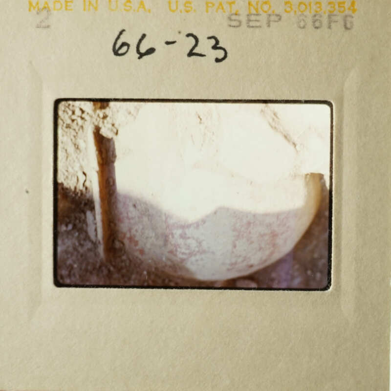 An aged photograph of a rock with a hole, taken from above.