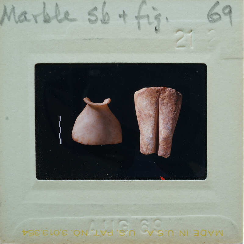 Photo of two ancient clay figurines on a white background with a label.