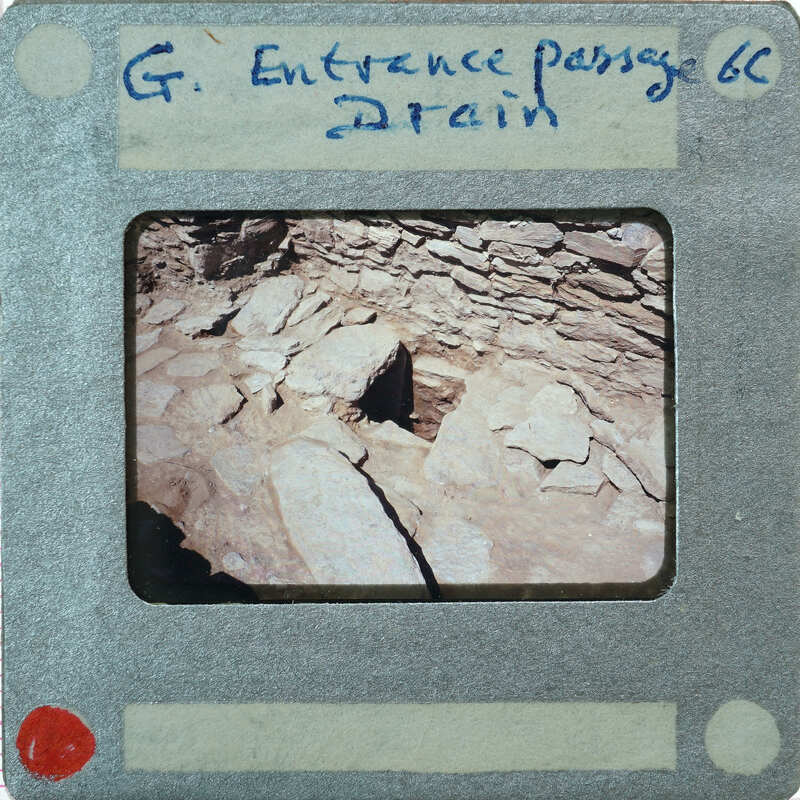 A photograph of a drain with handwritten labels on the border.