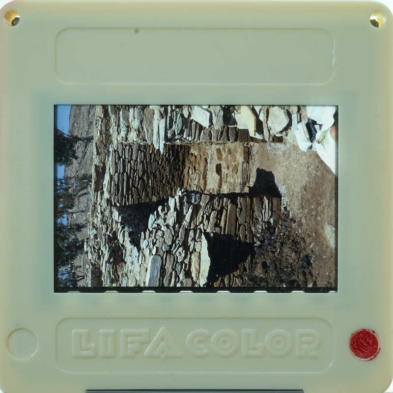 A small, colorful digital camera displaying a photo of an old stone structure.