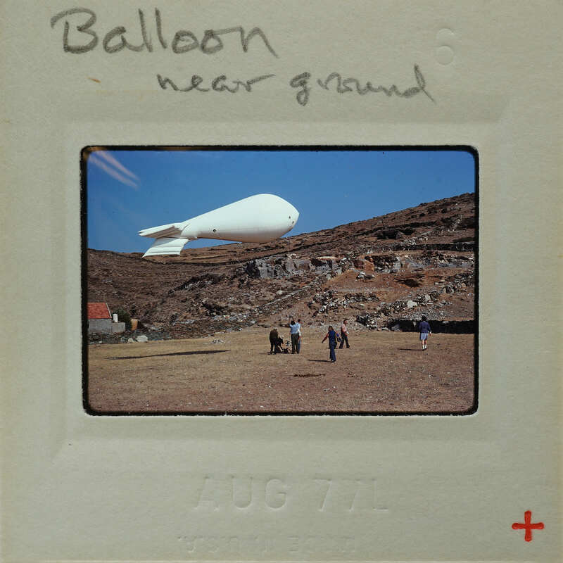 A large balloon on the ground with people standing around it.