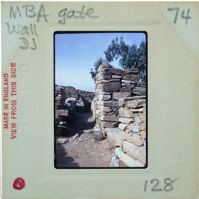 Old stone ruins with trees and a clear sky, captured on an analog film strip.