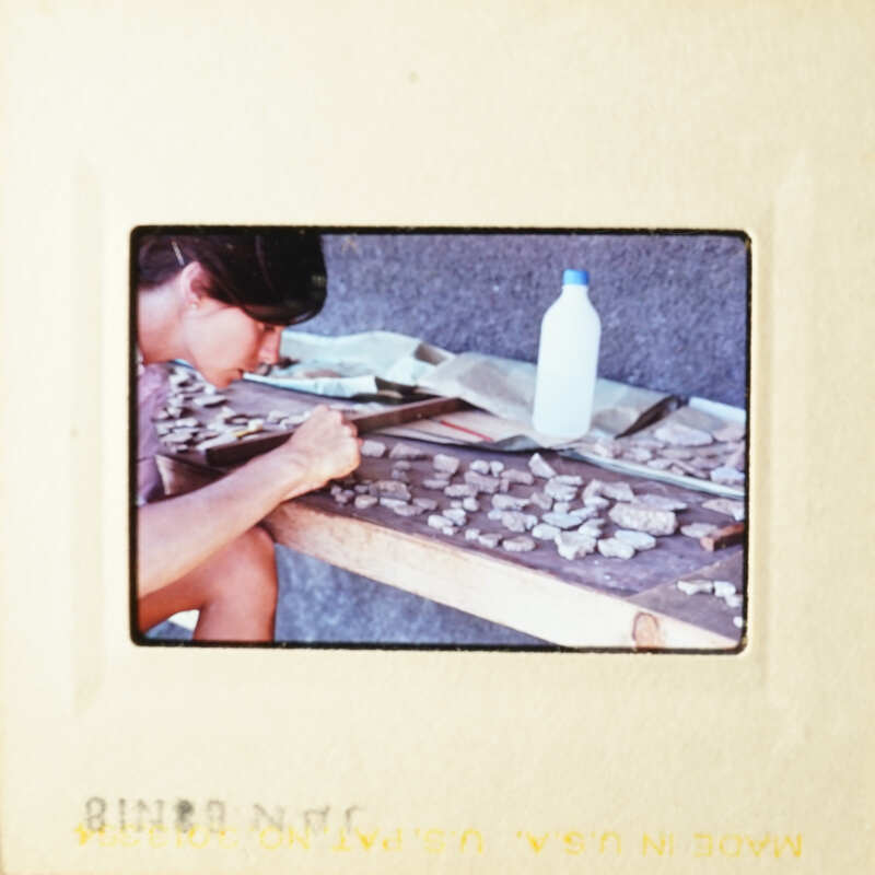 Woman working on art project at table with various materials.