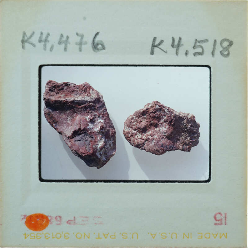 Two small, brownish rocks on a white surface with labels and numbers around them.