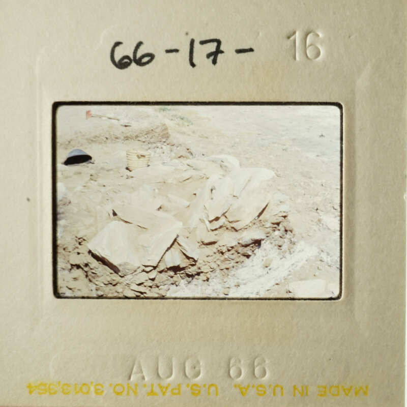 A photo of a pile of stones, possibly from an archaeological site, with a handwritten note on the bottom left corner.