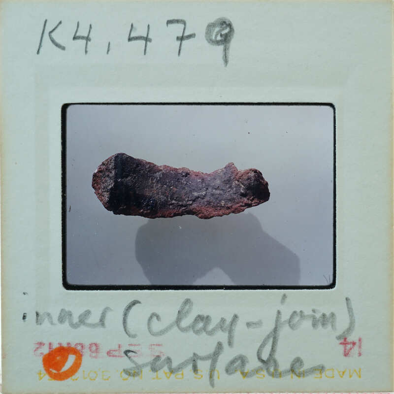 A slide of a clay-like object with annotations on the back.