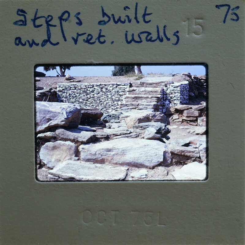 The image is a photograph of an old stone structure, possibly ruins, with a focus on the steps and walls made of stacked stones.