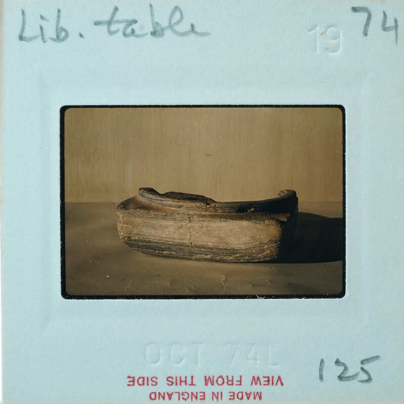 Fragment of squared off stone with rim and circular impression on top.