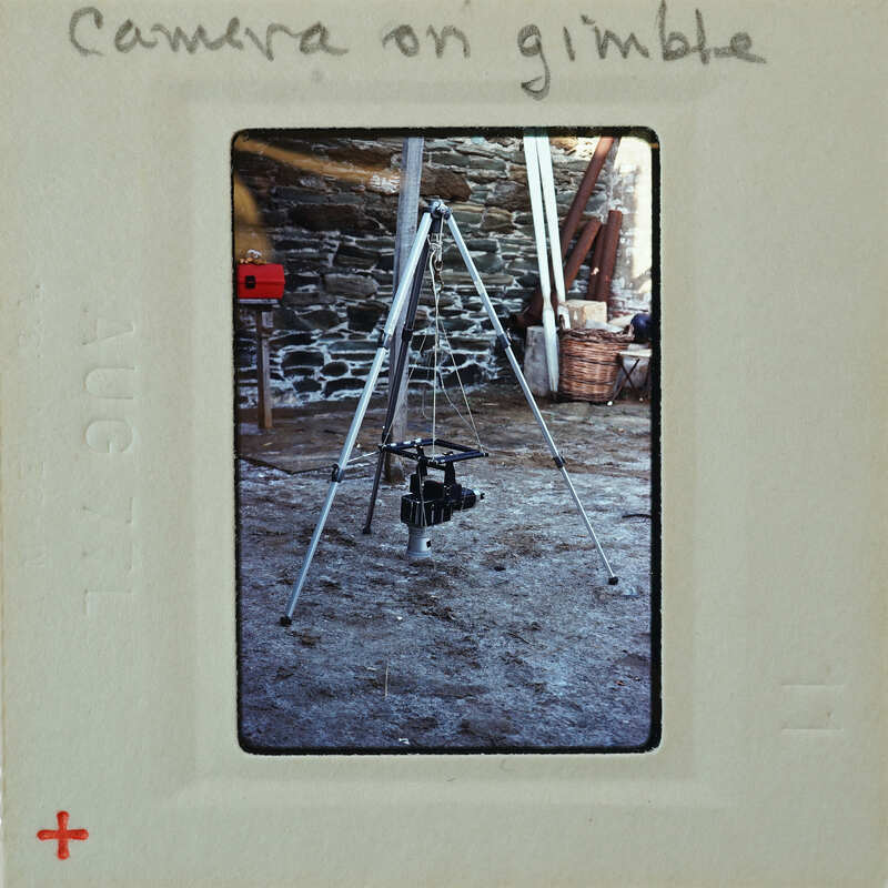 Camera tripod with camera on top, set up outdoors.