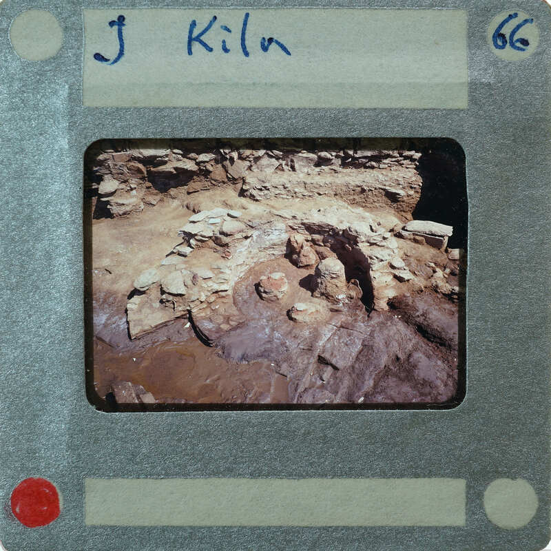 A photograph of an archaeological site with ruins and a label indicating it was taken by J. Kiln, number 66.