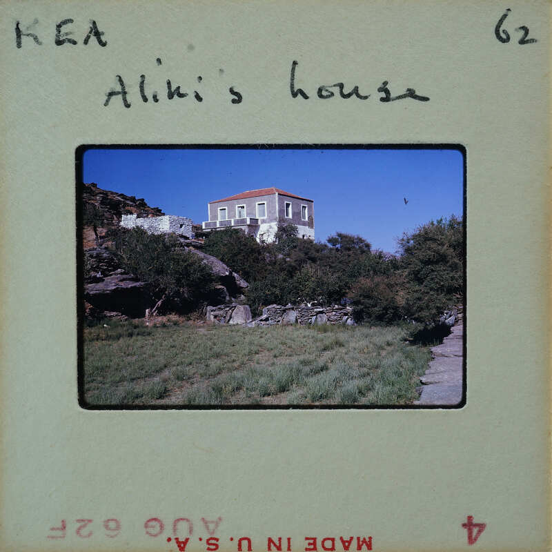 A vintage photo of a house on a hillside with trees and rocks.