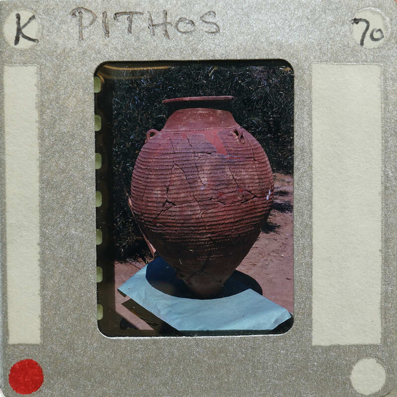 A photograph of a large, cracked clay pot on table.