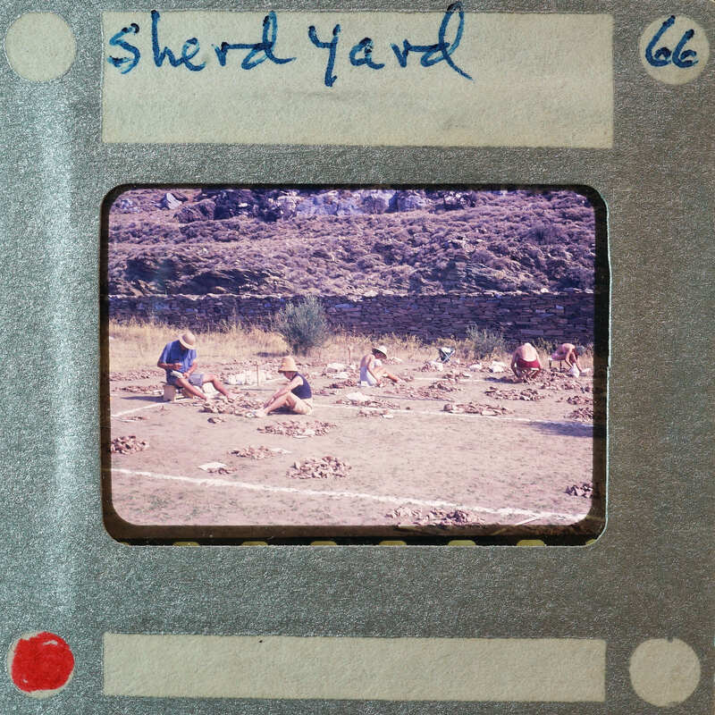 A vintage photo of a group of people working on a field with rocks, set within an old film strip frame.