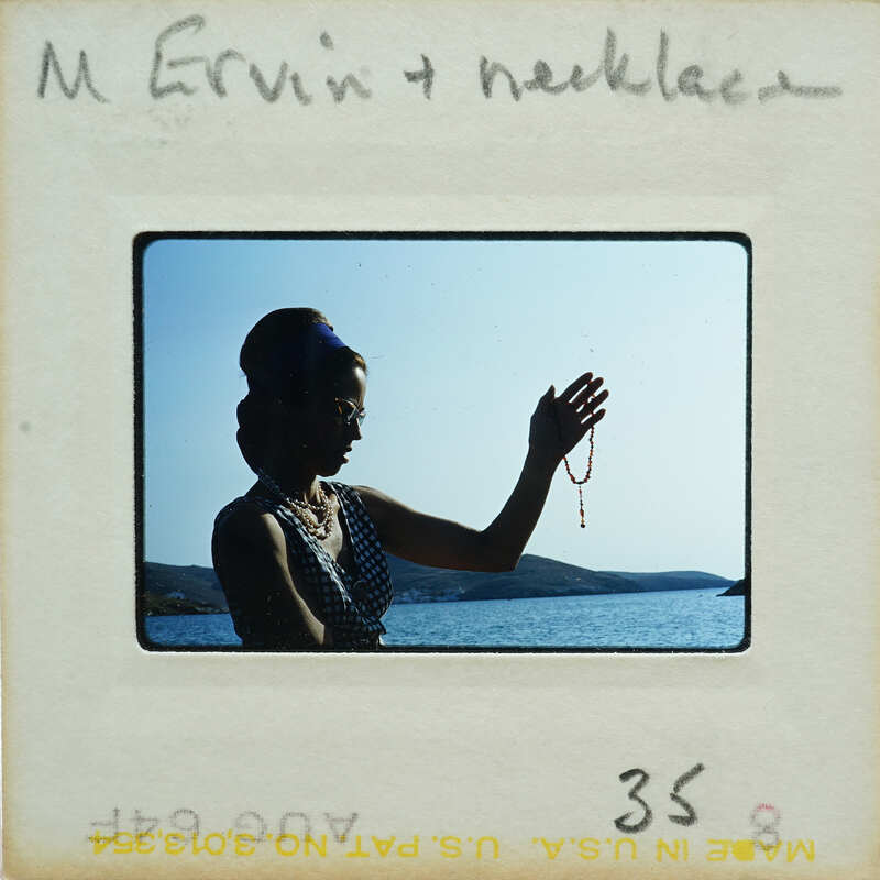 Woman holding a necklace by the water.