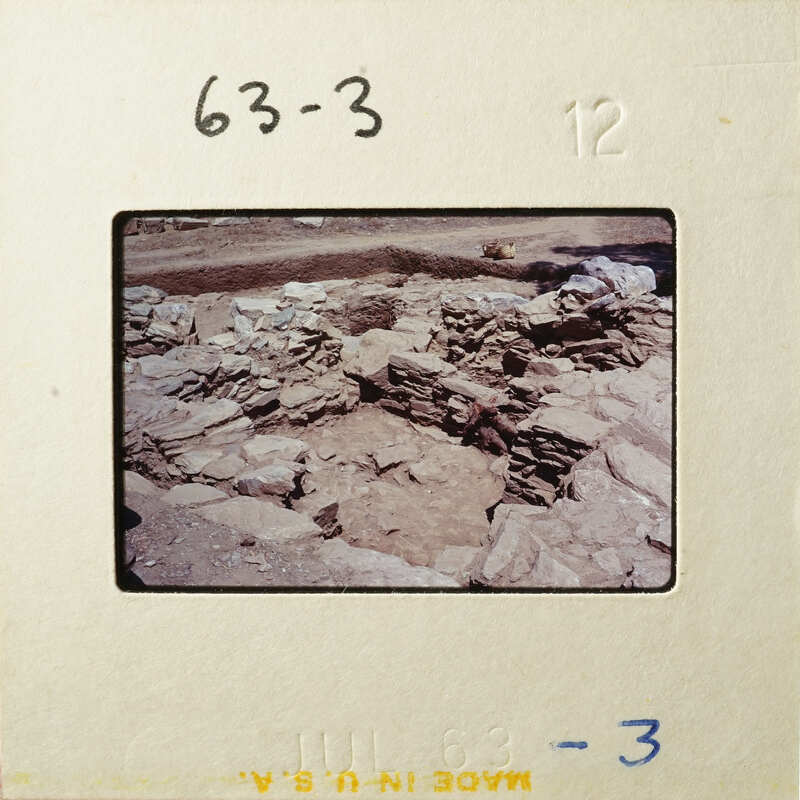 Ancient ruins with stone walls and dirt ground.