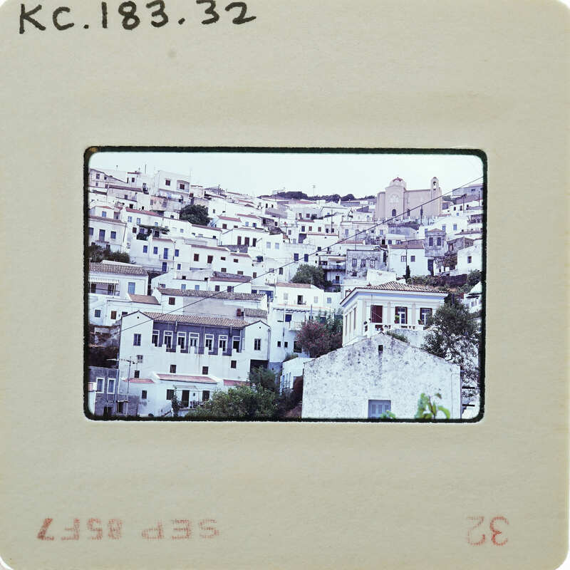 A vintage photo of a coastal town with white buildings and blue roofs, printed on an old-fashioned film strip.