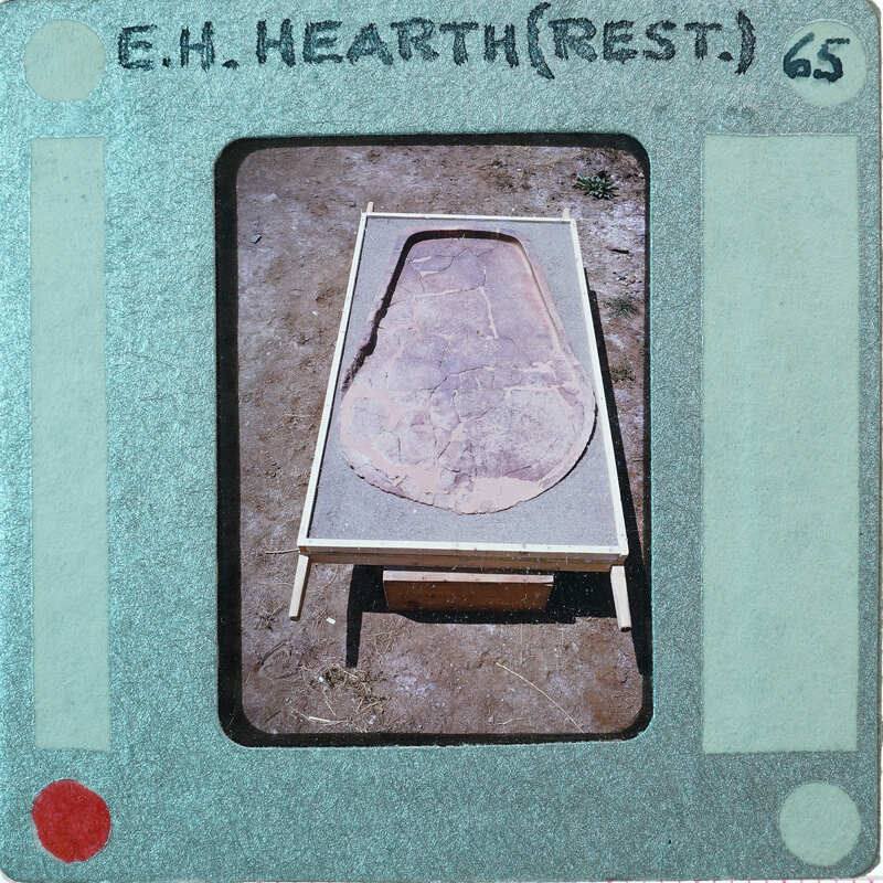 A photograph of a stone bed with a wooden frame, taken from an old Polaroid photo.