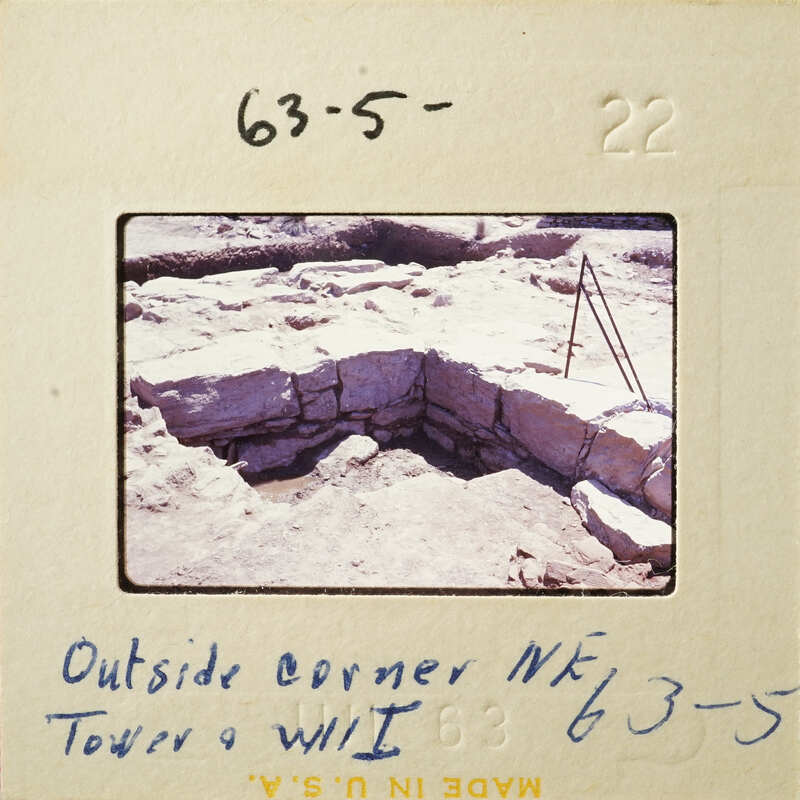 A photograph showing an excavation site with stone ruins and a small tent set up nearby.