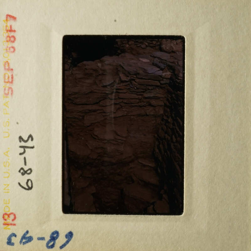 A photograph of an open film cartridge with a dark brown, possibly rocky interior.